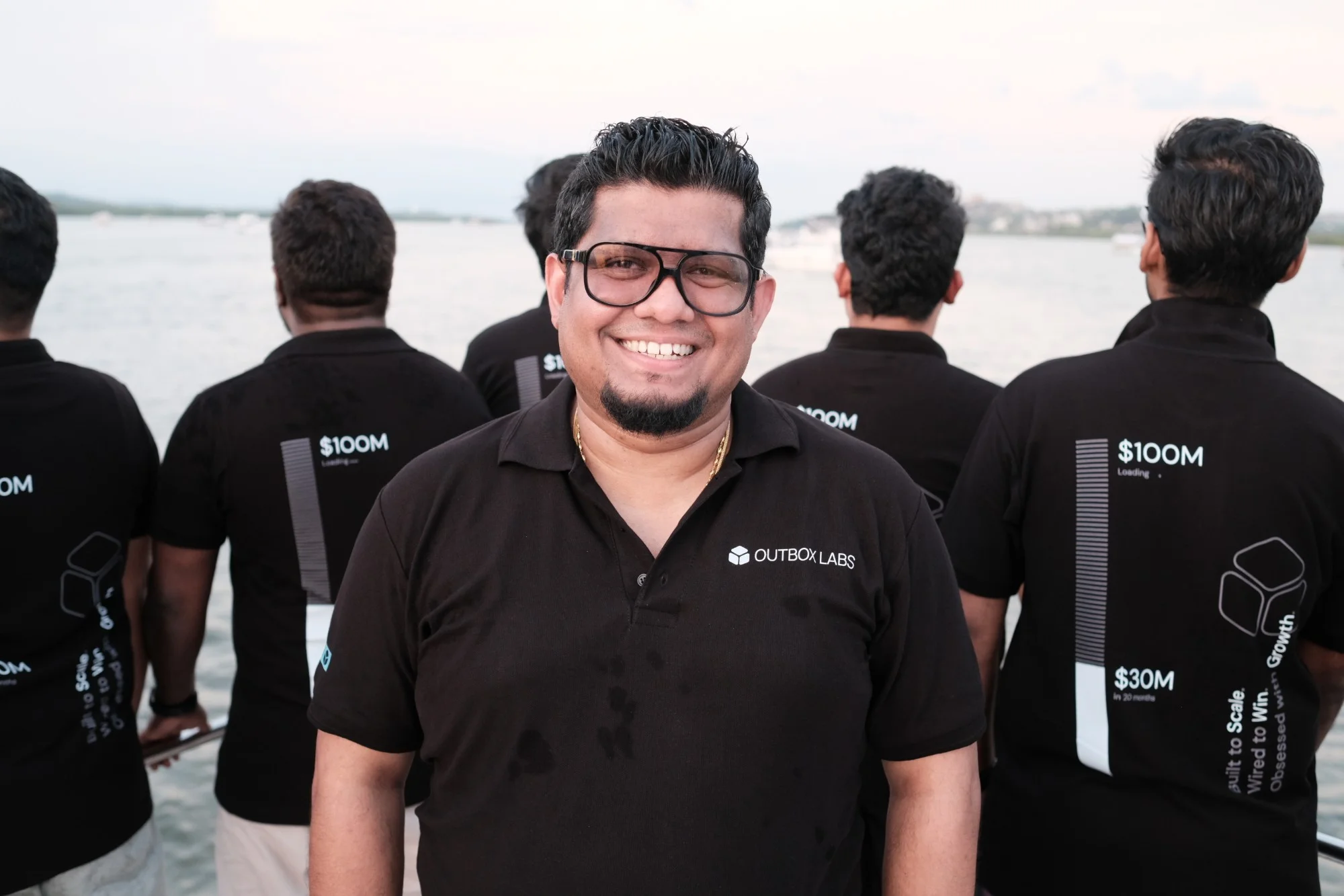 Alan smiling on the boat, the team behind him in their $100M polos