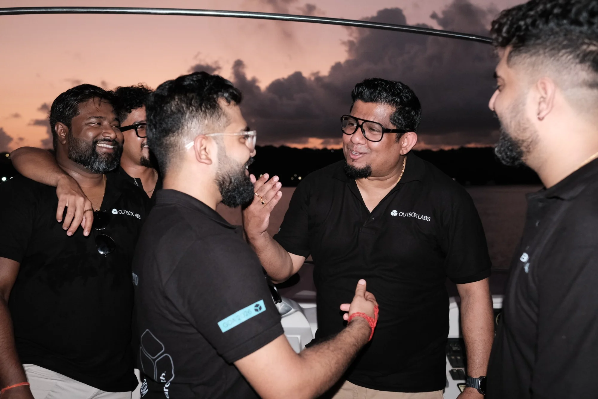 Alan laughing with the team on deck at sunset