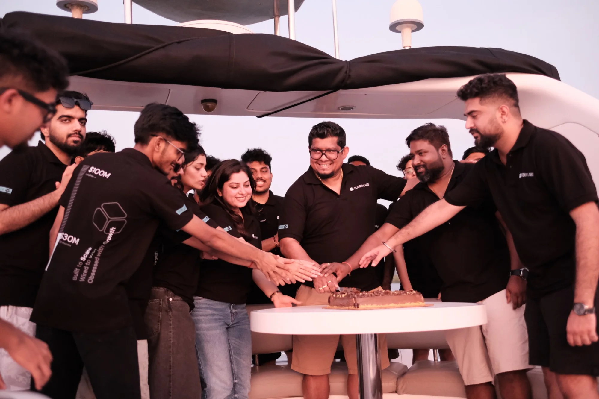 Alan cutting a cake on the boat, the whole team reaching in